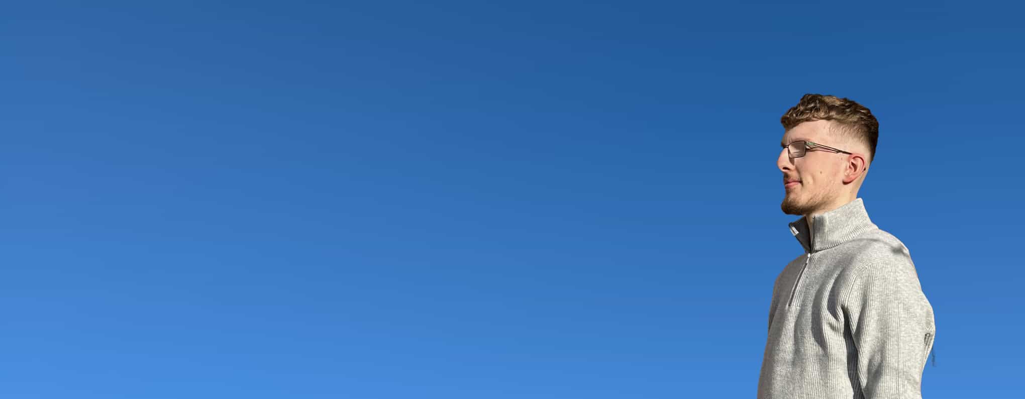 Jordan Johnson standing against a blue sky looking to the left