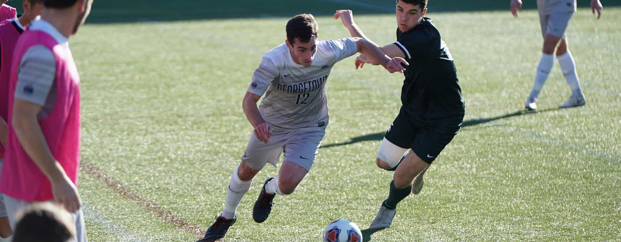 A footballer wearing white sprints past a footballer wearing black.