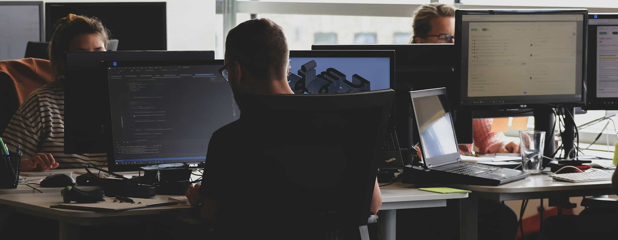 Three people sitting working in an office.