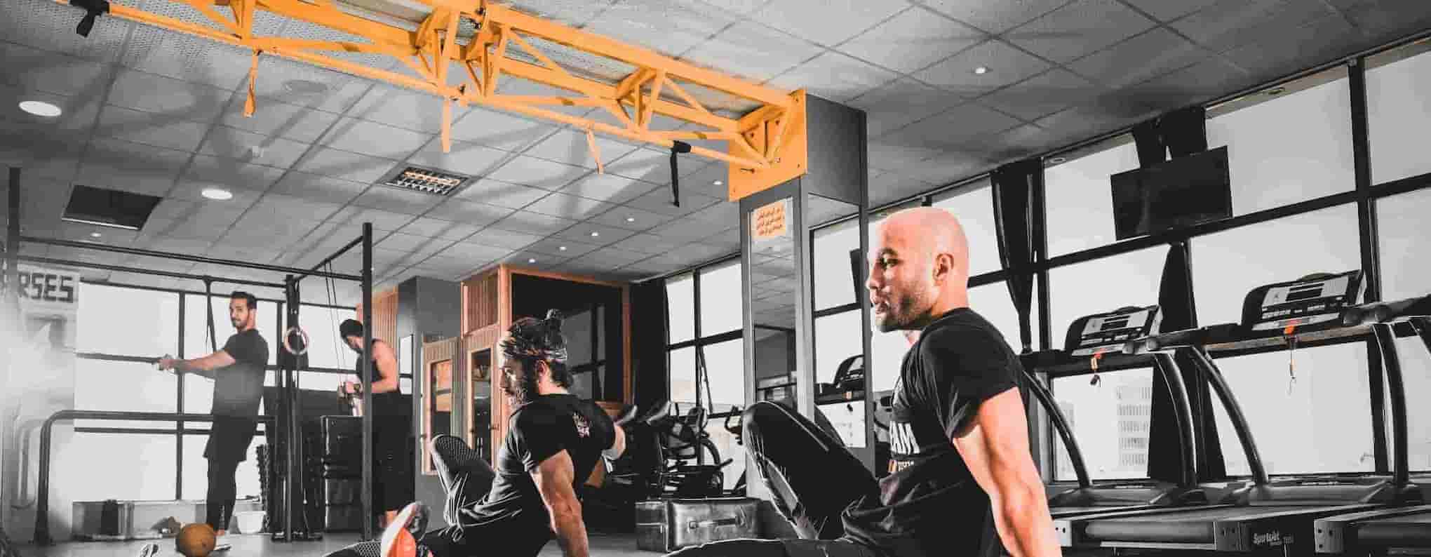 A gym setting with 2 men working out in the foreground