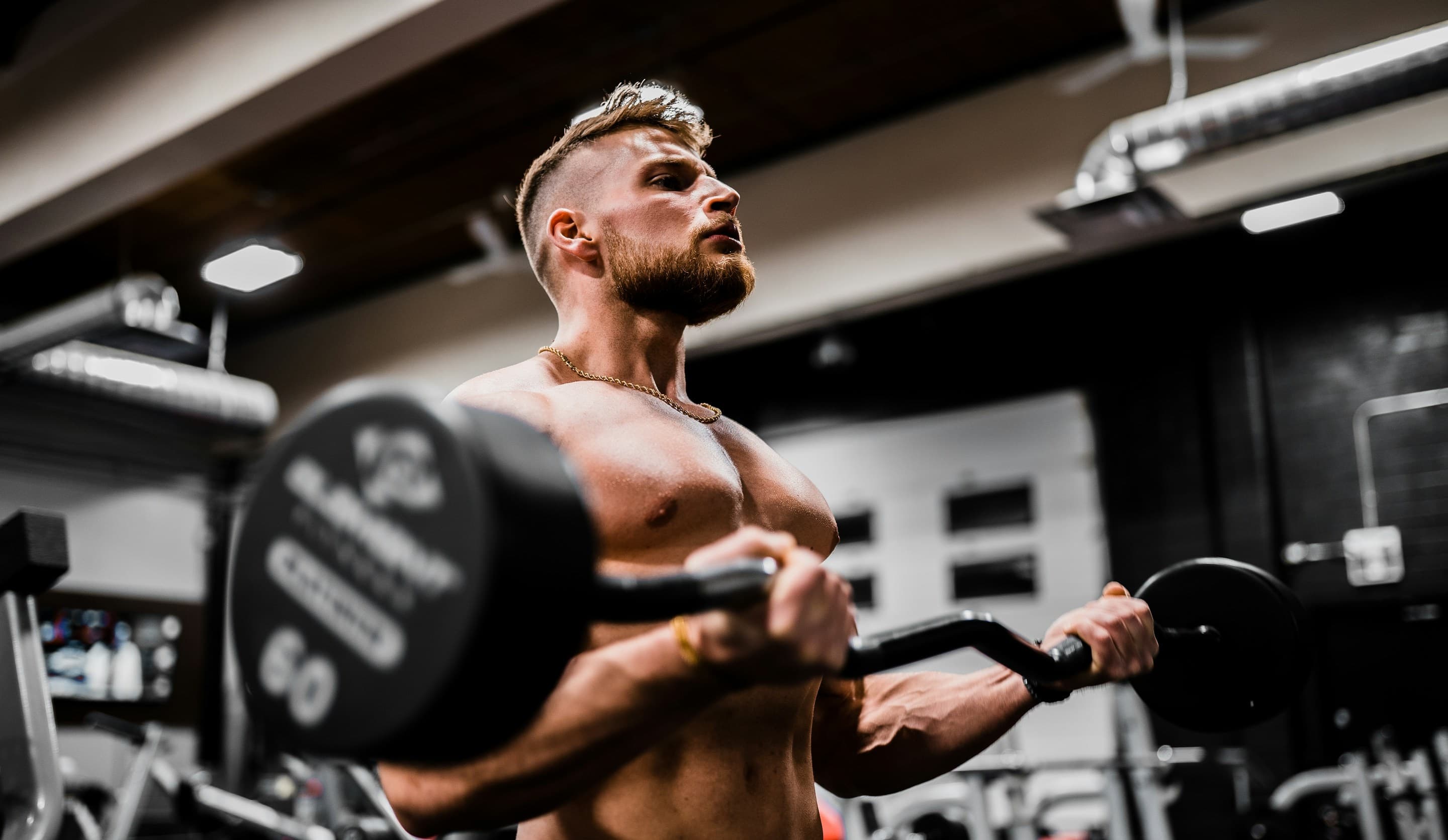 A topless man doing bicep curls
