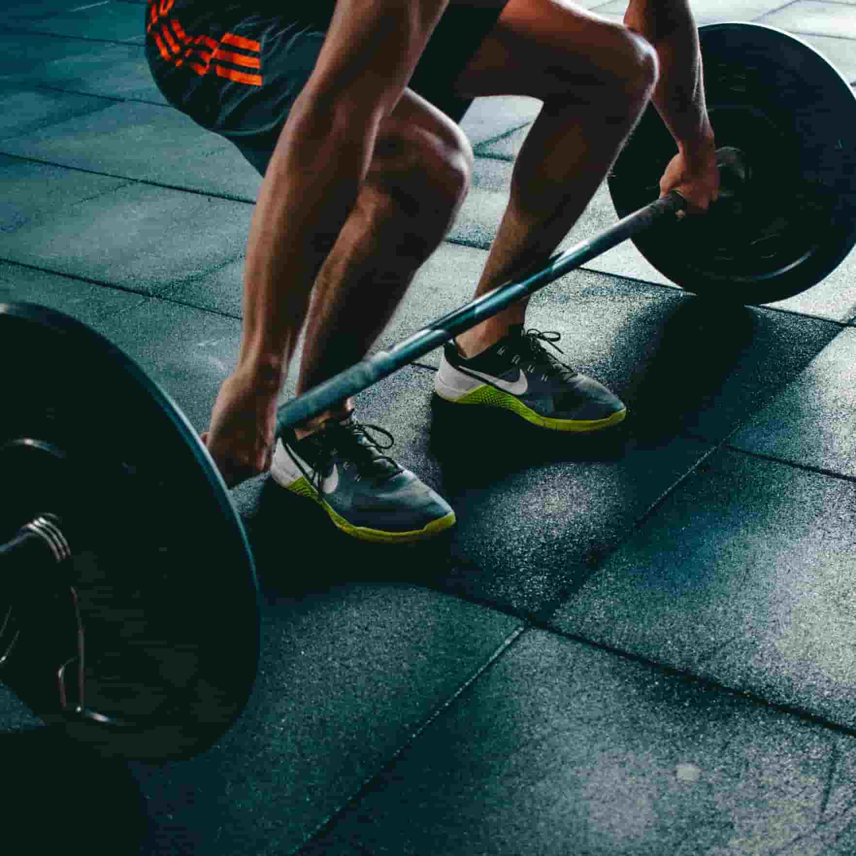 A man holding a barbell in the deadlift starting position
