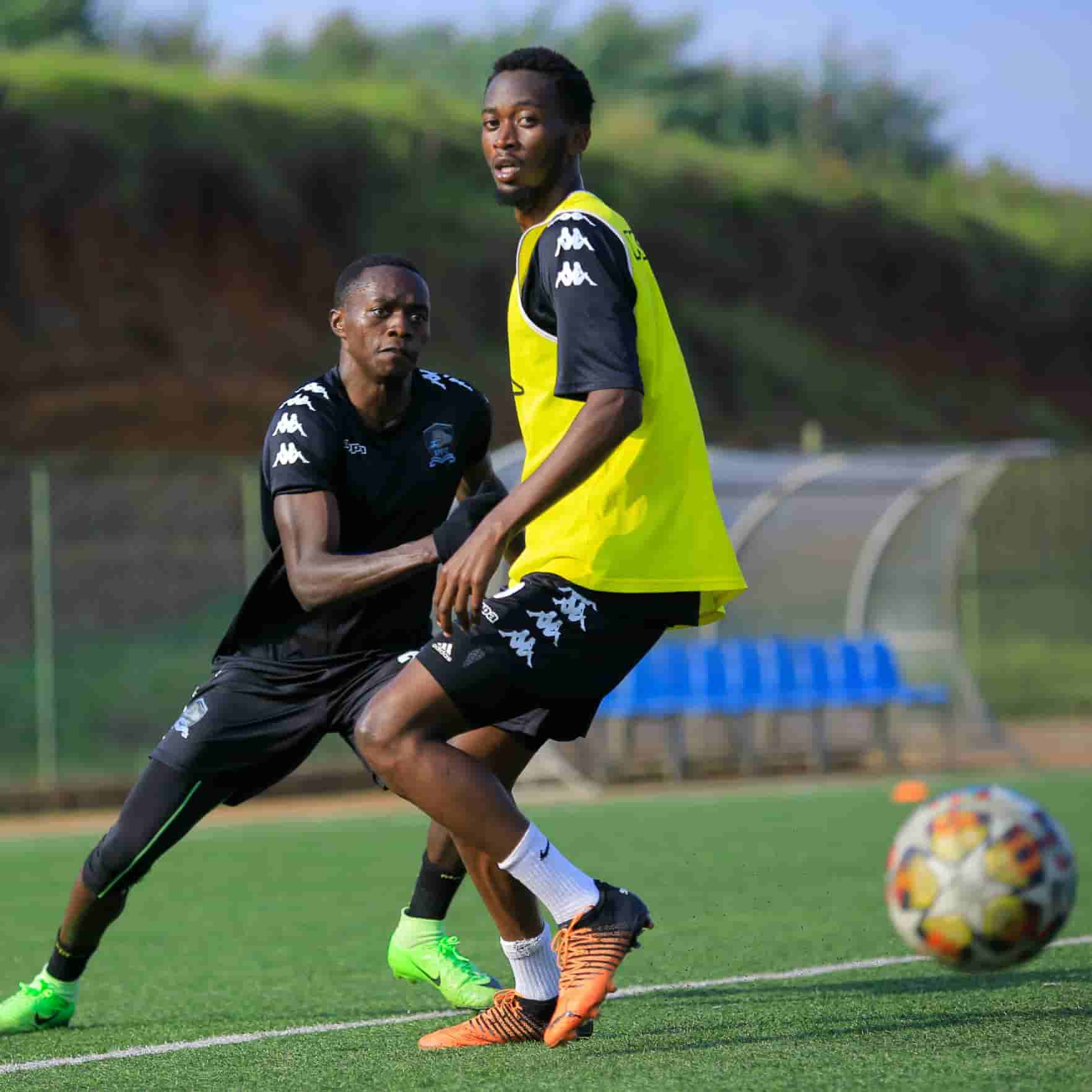 Two men playing football on opposing teams, both challenging for the ball