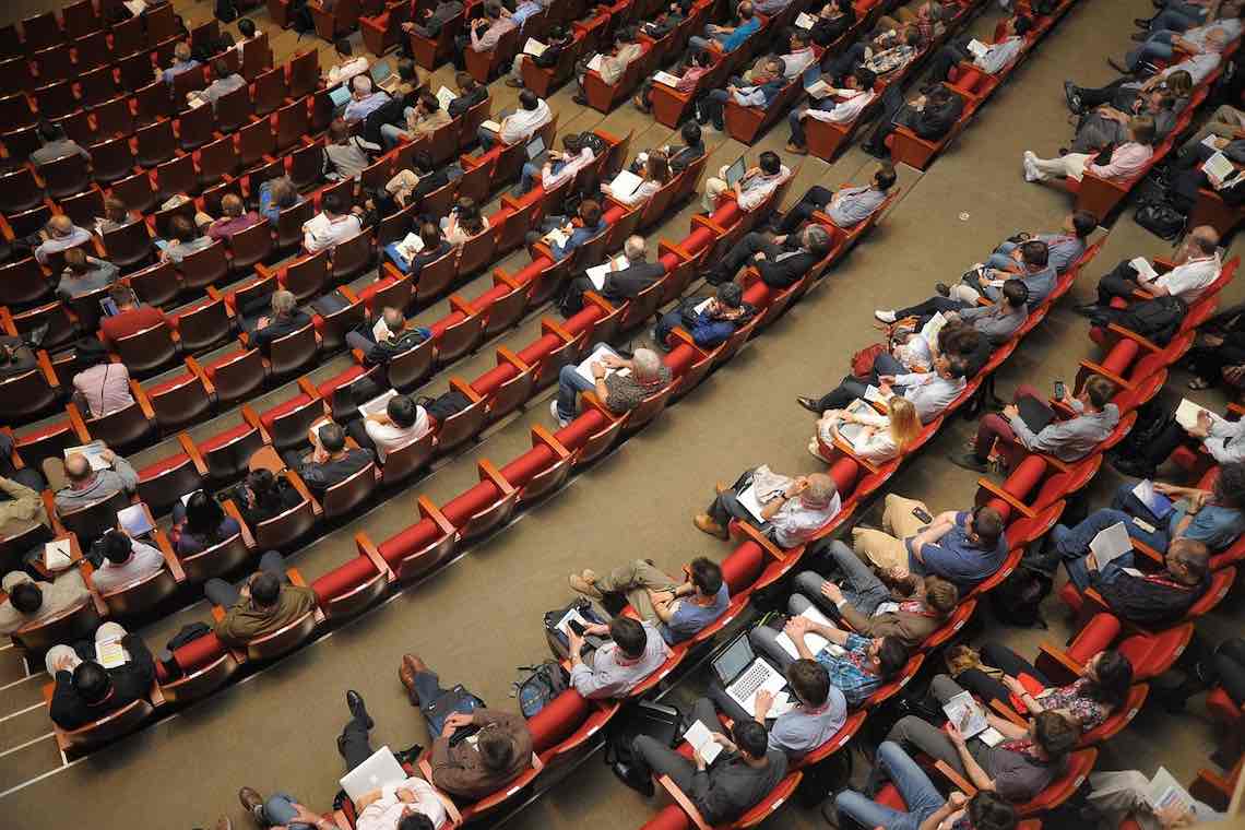 A large conference room viewed from above with a few empty seats.
